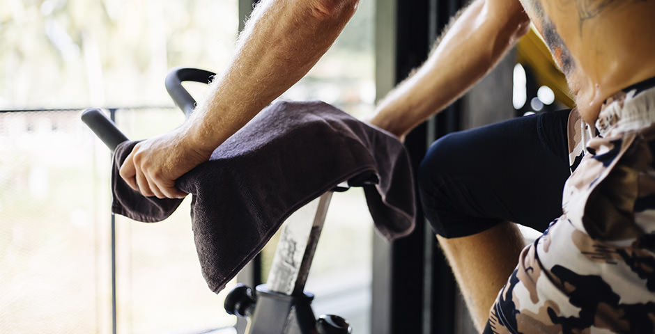 Tattooed person sweating on an indoor bike