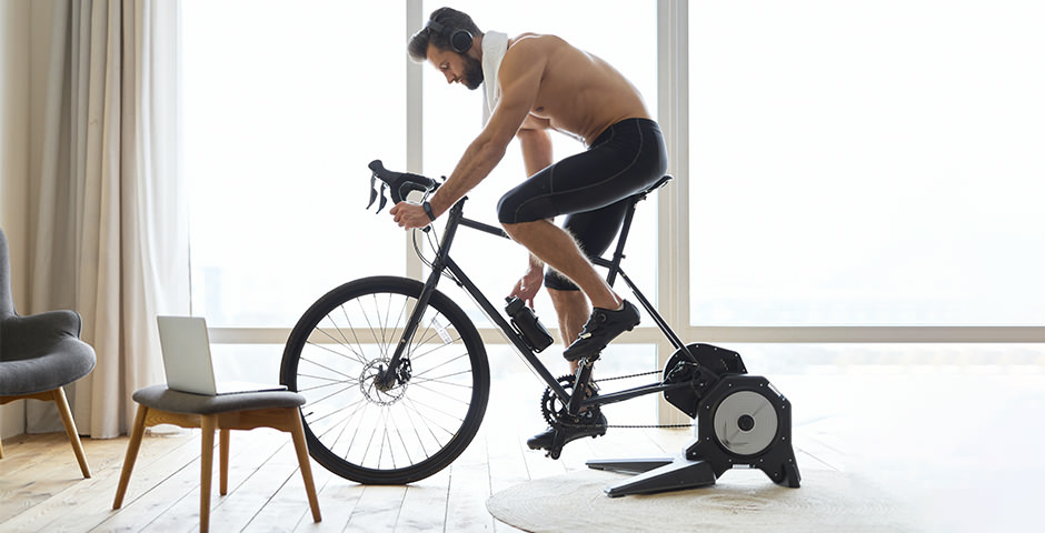 un hombre pedalea en una bicicleta estática, realizando una sesión de descanso activo en ciclismo